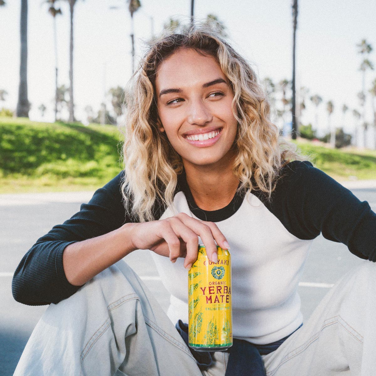 Person smiling and holding up a Guayaki Yerba Mate can.