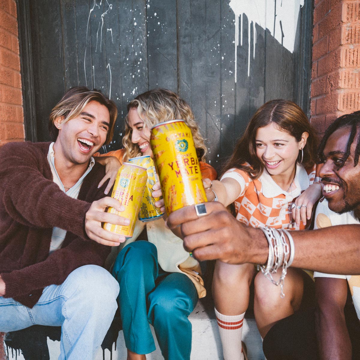 4 people smiling and holding up Guayaki Yerba Mate cans.
