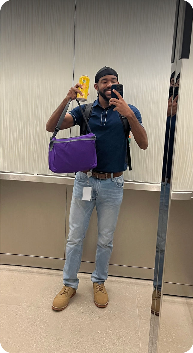 Xavier Brown holding a Yerba Mate can and taking a mirror picture with his phone.