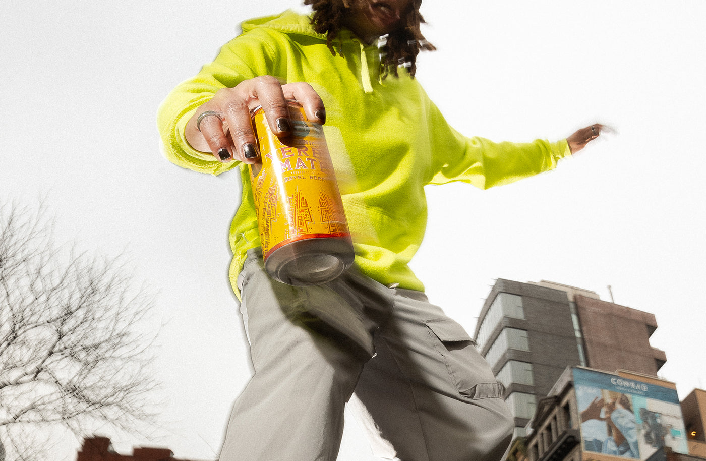 Young person in a neon green sweatshirt holding a can of Yerba Madre